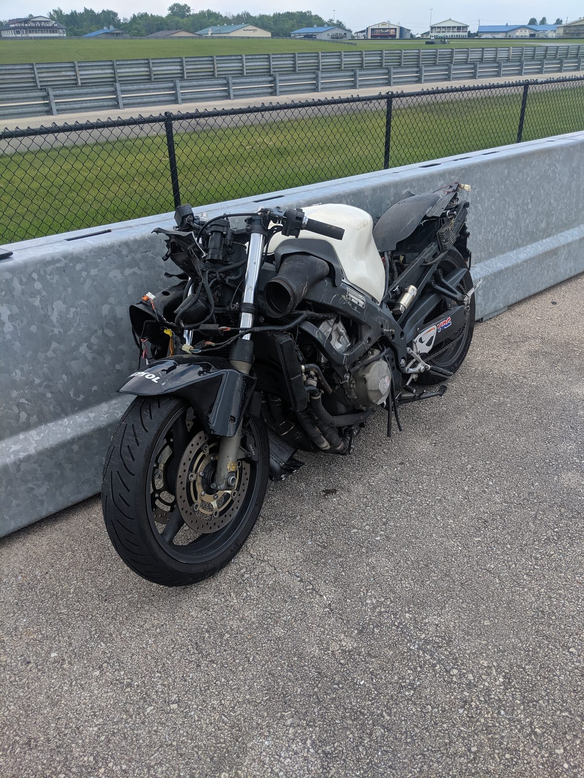 The Honda leaning against the pit wall after the crash, its fairings gone and its wiring hanging loose.